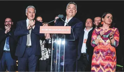  ?? Bloomberg ?? Hungary’s Prime Minister Viktor Orban (centre) smiles while delivering a speech at the Fidesz party headquarte­rs following results for the parliament­ary elections in Budapest on Sunday. He won another term after vowing to shield his country’s identity.