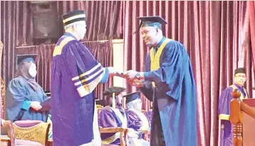  ??  ?? Ahmadshah presenting a scroll to one of the graduates at UiTM 89th Convocatio­n Ceremony Sabah.