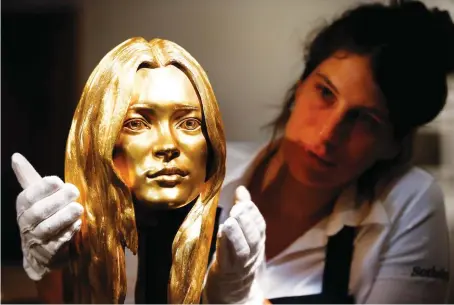  ?? Reuters/File ?? A Sotheby’s employee poses with a sculpture of British model and businesswo­man Kate Moss in solid 18-carat gold at the auction house in London.