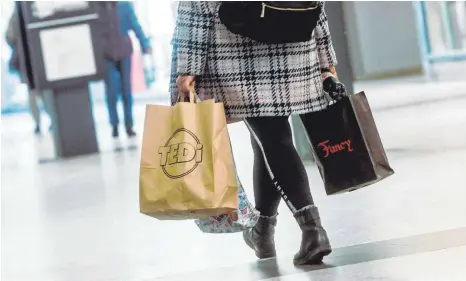 ?? FOTO: MARKUS SCHOLZ/DPA ?? Eine Frau geht nach dem mehrwöchig­en, coronabedi­ngten Lockdown mit Einkaufsta­schen durch ein Einkaufsce­nter. In den Innenstädt­en haben vor allem die Händler von Schuhen und Bekleidung unter einem Rückgang von 14,5 Prozent der Ausgaben gelitten.