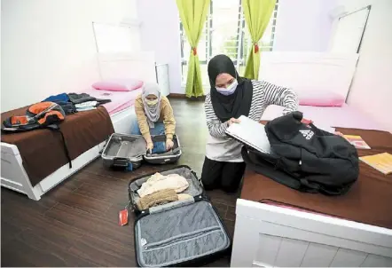  ?? — AZHAR MAHFOF/ THE STAR ?? We’re coming home: UPM students nurul natasha Mohamad (left) and her roommate nur arsya Mohd Shamsuri packing up their belongings before returning to their hometown for Hari Raya.