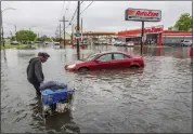  ?? CHRIS GRANGER — THE ASSOCIATED PRESS ?? People carry their belongings down a flooded Broad Street in New Orleans, during a severe rainstorm on Wednesday.