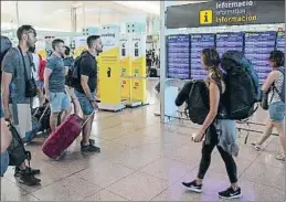  ?? MANÉ ESPINOSA ?? Pasajeros en El Prat frente a las pantallas de informació­n