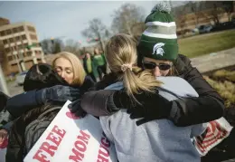  ?? JAKE MAY/THE FLINT JOURNAL ?? Spartan hug: Sue Dodde, a mother from Conklin, Michigan, right, embraces a student with a “free hug from a mom” as the campus reopened for classes Monday at Michigan State University in East Lansing, Mich. One week ago, three students were killed and five others were injured during a mass shooting at the university.