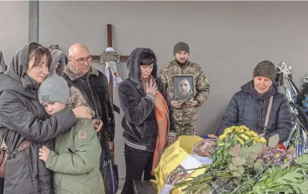  ?? ROMAN PILIPEY/AFP VIA GETTY IMAGES ?? Family members of Ukrainian service member Andriy Katanenko, 39, who was killed near Avdiivka, mourn next to his coffin Saturday during a funeral ceremony in Bucha, northwest of Kyiv, Ukraine.