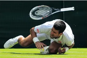  ?? CARL COURT/ GETTY IMAGES ?? Serbia’s Novak Djokovic falls awkwardly and hurts his left shoulder during a point against France’s Gilles Simon during men’s singles third-round action at Wimbledon on Friday.