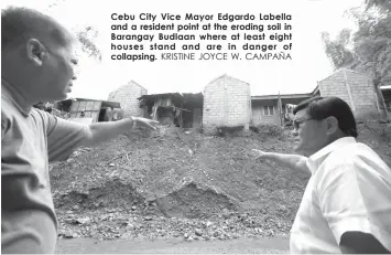  ?? KRISTINE JOYCE W. CAMPAÑA ?? Cebu City Vice Mayor Edgardo Labella and a resident point at the eroding soil in Barangay Budlaan where at least eight houses stand and are in danger of collapsing.