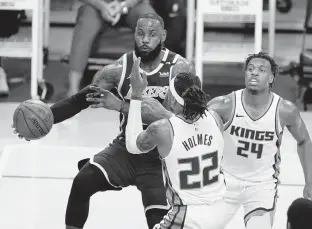  ?? MARCIO JOSE SANCHEZ/AP ?? Los Angeles Lakers forward LeBron James, pictured passing the ball around Sacramento Kings center Richaun Holmes on April 30, has missed 23 of the past 25 games with a high ankle sprain.