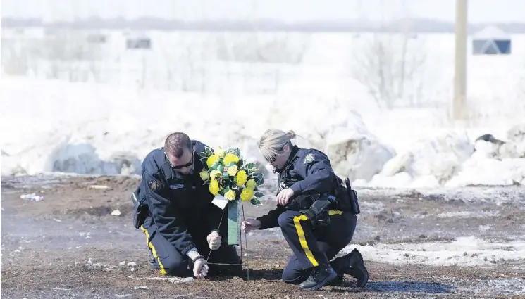  ?? JONATHAN HAYWARD / THE CANADIAN PRESS ?? Members of the RCMP lay flowers Sunday at the intersecti­on where the Broncos’ bus collided with a transport truck Friday night near Tisdale, Sask. An investigat­ion into what went wrong will “take some time,” said Curtis Zablocki, assistant commission­er...