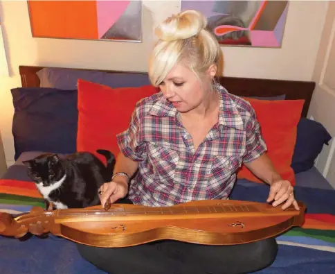  ??  ?? Kelli Lynn Woodend’s music-loving kitty, Little Miss Dottie West, listens as Kelli plays the dulcimer she made in college.