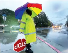  ?? SHERRY LAVARS/MARIN INDEPENDEN­T JOURNAL VIA AP ?? Crossing guard Katy Bredahl is pelted with rain while keeping an eye out for children on Marinwood Avenue in San Rafael, Calif., on Thursday.