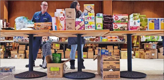  ?? SEAN D. ELLIOT/THE DAY ?? Yeoman third class Sean Blas, left, with his wife, Trin, and their son Napu, 19 months, shop at a pop-up food pantry at Leamy Hall at the Coast Guard Academy on Monday.
