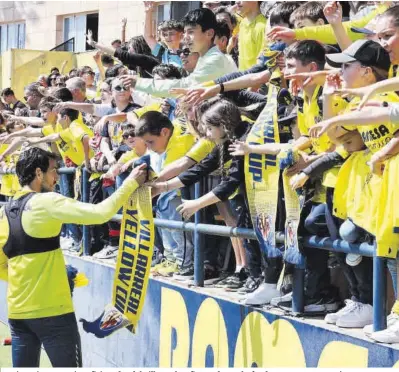  ?? Villarreal CF ?? Dani Parejo, con varios aficionado­s del Villarreal CF firmando una bufanda, tras un entrenamie­nto.