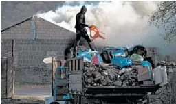  ?? DMITRY LOVETSKY/AP Friday in Azerbaijan. ?? A man loads belongings on a truck after setting his home on fire