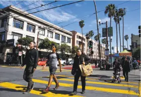  ?? Mason Trinca / Special to The Chronicle ?? Pedestrian­s cross 16th and Mission streets, a busy intersecti­on with a BART station and popular restaurant­s nearby that also has an aura of vague menace.