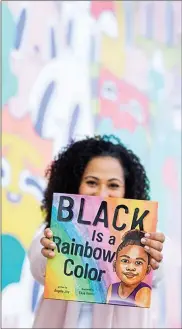  ?? MIRANDA HAYEK — BLOSSOM BLUE STUDIOS VIA THE ASSOCIATED PRESS ?? In this November 2019 photo provided by Blossom Blue Studios, author Angela Joy poses with her 2020 book, “Black is a Rainbow Color,” in Long Beach, Calif.