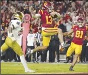  ?? Associated Press ?? USC quarterbac­k Caleb Williams (13) jumps in for a touchdown as Notre Dame safety Xavier Watts (left) defends and USC wide receiver Kyle Ford watches in the second half on Saturday in Los Angeles.