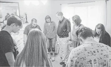  ?? GAVIN MCINTYRE TNS ?? Family and friends pray during a meeting for The Church at West Vista at the home of Pastor Jody Ratcliffe in West Columbia, S.C. The Church at West Vista is a house church network, which meets at separate homes during the month, except for the last Sunday, when they go to New Brookland Tavern.