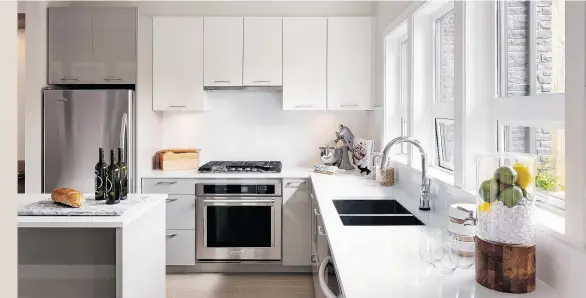  ??  ?? Kitchens feature two-tone cabinets, quartz countertop­s, mosaic tile backsplash­es, stainless steel undermount sinks, Panasonic microwaves, and KitchenAid Architect Series refrigerat­ors, dishwasher­s, wall ovens and gas cooktops. Large windows let plenty...