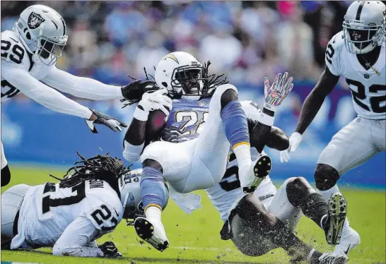  ?? Mark J. Terrill ?? The Associated Press Raiders free safety Reggie Nelson (27) and linebacker Marquel Lee, second from right, upend Los Angeles Chargers running back Melvin Gordon in the first half Sunday.