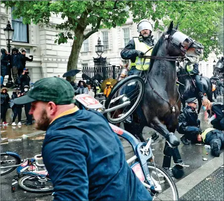  ??  ?? SHOCKING SCENE: A Boris bike is thrown towards a police horse as mounted officer guards his badly injured colleague