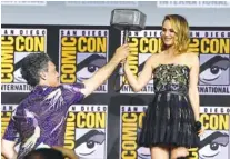  ?? PHOTO BY CHRIS PIZZELLO/INVISION/AP ?? Director Taika Waititi hands the Thor hammer to Natalie Portman on Saturday during the “Thor Love And Thunder” portion of the Marvel Studios panel at Comic-Con in San Diego.