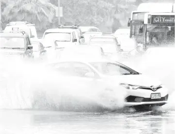  ??  ?? A car drives through water, caused by heavy rain, on a road in Sydney. — AFP photo