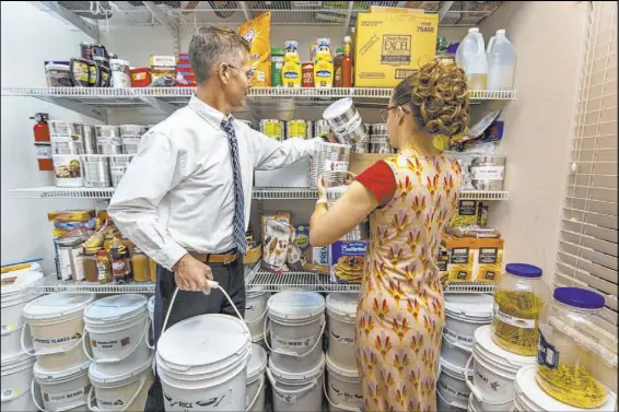  ?? L.E. Baskow Las Vegas Review-Journal @Left_Eye_Images ?? Cory and Holly Steed sort through some of the food items stored in their home pantry on Monday in Las Vegas. Their LDS church encourages its members to be prepared for emergencie­s by keeping food, water and safety equipment on hand.