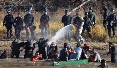  ?? JASON PATINKIN / REUTERS ?? Police use pepper spray against protesters trying to cross a stream near an oil pipeline constructi­on site near Standing Rock Indian Reservatio­n, north of Cannon Ball, North Dakota on Wednesday.