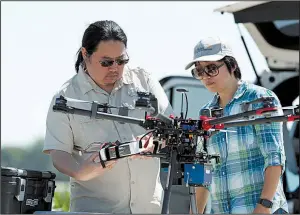  ?? AP/DAVID ZALUBOWSKI ?? Engineerin­g technician Kevin Yemoto (left) and Huihui Zhang work on the camera on a drone at a USDA research farm northeast of Greeley, Colo.