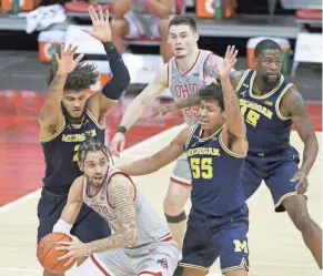  ?? BARBARA J. PERENIC/COLUMBUS DISPATCH ?? Ohio State guard Duane Washington Jr. is guarded by Michigan’s Isaiah Livers (2) and Eli Brooks (55) during Sunday’s Big Ten conference basketball game in Columbus.