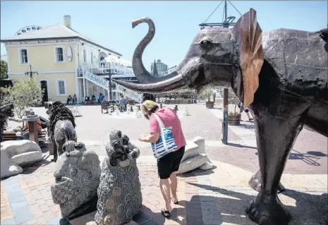  ?? PHOTO: BLOOMBERG ?? A tourist ducks beneath the tusks of an elephant sculpture in the Victoria & Alfred Waterfront in Cape Town. The tourism industry’s contributi­on to gross domestic product grew from R372 billion in 2014 to R375bn in 2015.