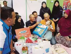  ?? [ FOTO ADZLAN SIDEK/BH ] ?? Ahmad Wafit lima tahun di dukung ayahnya, Adli Isham menerima sumbangan daripada Rosly (tiga dari kiri) di Taman Rasah Jaya, Seremban.