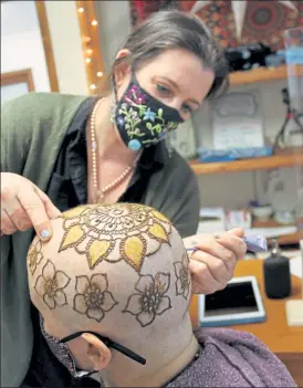  ?? DANIELLE RAY PHOTOS / SENTINEL & ENTERPRISE ?? Mandy Roberge applies henna artwork to Michelle Behr’s head with an ornate mandala style design at her Leominster. studio, Wicked Good Henna. At top is the end result.