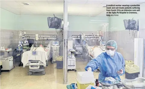  ?? REUTERS ?? A medical worker wearing a protective mask and suit treats patients suffering from Covid-19 in an intensive care unit at the Oglio Po Hospital in Cremona, Italy.