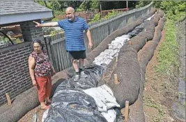  ?? Matt Freed/Post-Gazette ?? Sue and Daniel Armstrong stand along the sandbag dam built behind their house along Reissing Road on Friday after experienci­ng flooding from the constructi­on of the Southern Beltway in McDonald.