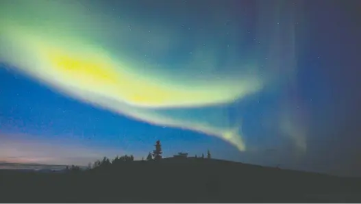  ?? DEBBIE OLSEN ?? The northern lights appear above Dawson City in the Yukon. The dark skies of winter are best for aurora viewing, but visitors can see them in mid-august in some locales.