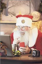  ?? Sisoje / Getty Images ?? Santa Claus using a computer in his house to do a Christmas video conference. He is typing his present list on the mobile phone.