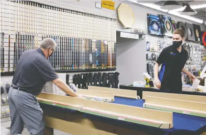  ?? MICHAEL BELL ?? Dave Swain and his son Spencer assemble a pool table at Royal Sporting Goods. The family business began as a pool hall in 1917, and over the years branched into an array of sporting goods. Swain says since the pandemic hit last March, they've seen a huge drop in sales.