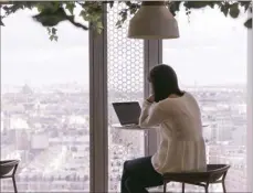  ?? LAURA STEVENS / BLOOMBERG ?? An employee works on a laptop by the beautiful city skyline at her company’s French headquarte­rs in Paris.