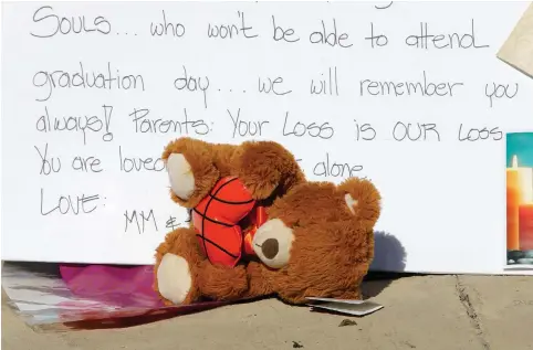  ?? (Jonathan Drake/Reuters) ?? A STUFFED TOY slumps over in front of a sign at a makeshift memorial on a fence close to Marjory Stoneman Douglas High School yesterday, three days after the school shooting in Parkland, Florida.