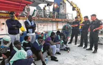  ?? Annalisa Camilli / Associated Press ?? Migrants sit on the quay Saturday after disembarki­ng at Lampedusa harbor in Italy. The captain of the ship carrying the migrants was arrested after ramming a border police motorboat.