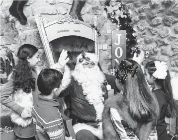  ?? DAVID VAAKNIN/FOR THE WASHINGTON POST ?? Issa Kassissieh, 40, greets children at Santa’s House in Jerusalem. “I am the only official Santa of the Holy Land,” he says.