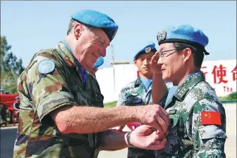  ?? PHOTOS BY LI LIANGYONG AND HUANG ZONGZHI / XINHUA ?? From top: Head of Mission and Force Commander Michael Beary of the United Nations Interim Force in Lebanon awards Huang Yunpei, commander of China’s Lebanon peacekeepi­ng team the peace medal; Han Zhuoqi (left) of China’s South Sudan peacekeepi­ng team walks off the plane and hugs his wife.
