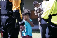  ?? JULIA WALL/RALEIGH NEWS & OBSERVER ?? Zoey Smith, 4, stands with her mother Krystale, who is holding her 2-month-old sister, Hailee, while Krystale receives informatio­n about nearby shelters from New York Urban Search and Rescue team members at the Heritage at Fort Bragg Apartments in Spring Lake, N.C., Tuesday. The family has been living out of their car since their ground floor apartment flooded earlier this week.