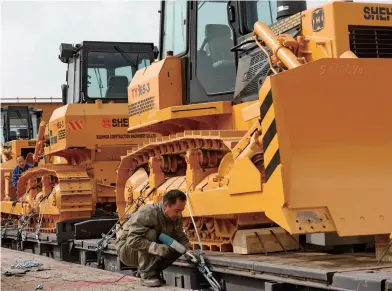  ??  ?? A worker from the HBIS Group Co. Ltd. loads bulldozers onto a train to be exported to Russia in Zhangjiako­u City, north China’s Hebei Province