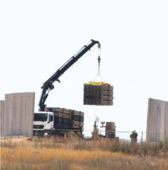  ?? (Reuters) ?? A TRUCK lowers an Iron Dome section onto a field to prepare for defensive operations.