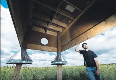  ?? CP PHOTO ?? Myles Falconer, senior project biologist at bird studies Canada poses for a photograph next to a custom built Barn Swallow nesting habitat in Townsend, Ont.