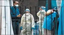  ?? KEVIN HAGEN/THE NEW YORK TIMES ?? Medical staffers chat Tuesday outside the virus testing facility at Elmhurst Hospital in the Queens borough of New York.