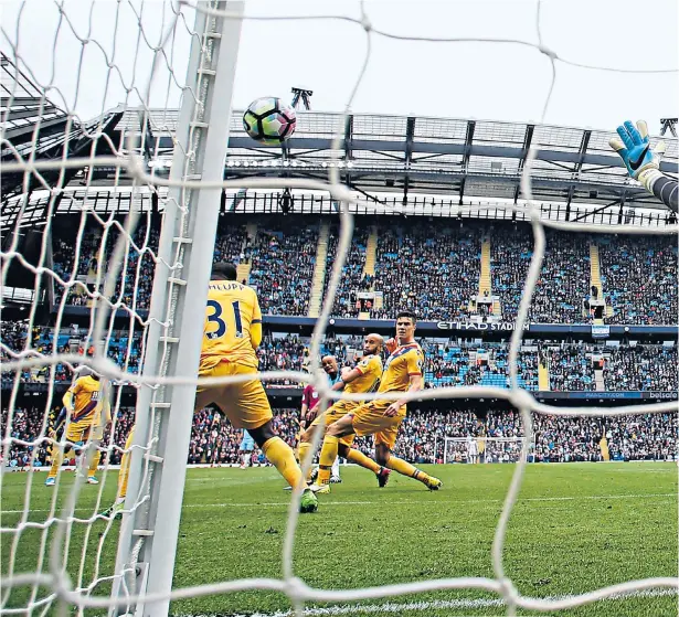  ??  ?? Out of reach: Wayne Hennessey, the Crystal Palace goalkeeper, is unable to stop Vincent Kompany scoring Manchester City’s second goal (above) while David Silva celebrates the first (right)